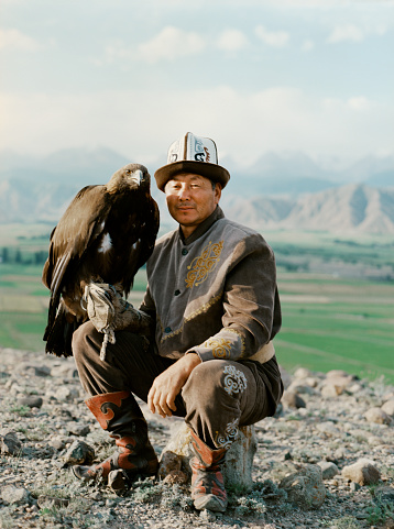 Eagle hunter sitting on the background of mountains  in Kyrgyzstan