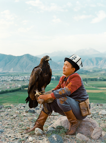 Eagle hunter sitting on the background of mountains  in Kyrgyzstan
