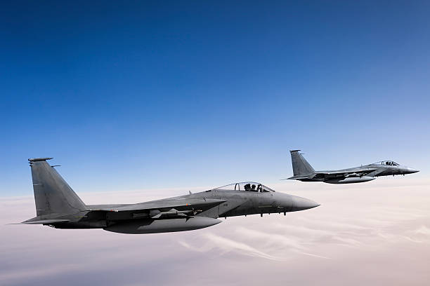 F-15 Eagles in Flight Two F-15 Eagle fighter jets flying above clouds defense industry stock pictures, royalty-free photos & images