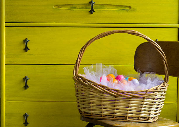 Easter Basket Sits In Front Of Yellow Vintage Dresser Stock Photo