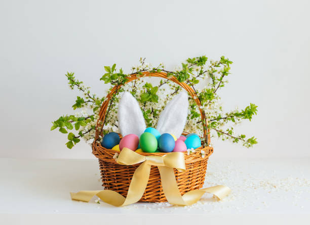 Easter basket with eggs and bunny ears on white background. Beautiful Easter composition. Festive decor. stock photo