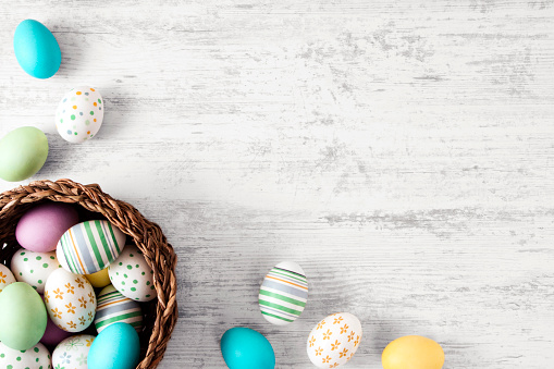 Pastel colored Easter eggs on white rustic background.
