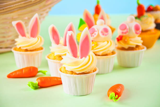 Easter funny bunny cupcakes. Easter celebration festive table. Basket of flowers tulips on the background. stock photo