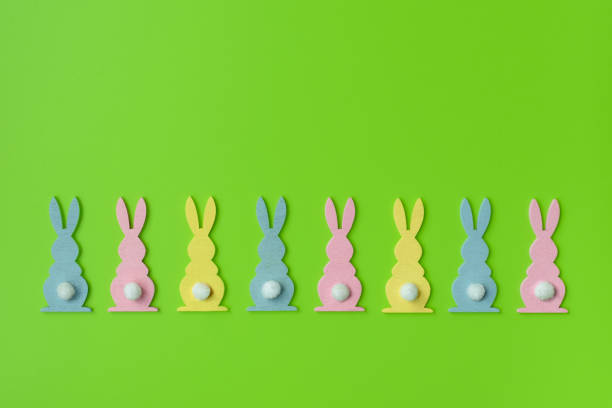Easter Holiday minimal concept. Row of decorative multicolored easter bunnies isolated on green background. Creative flat lay. For design cards or web banners. Copy space  easter sunday stock pictures, royalty-free photos & images