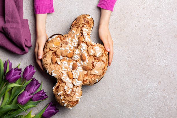 Easter tradition in Italy, Dove Cake topped with icing and almonds. Colomba di Pasqua.  Spring flowers. Top view. stock photo