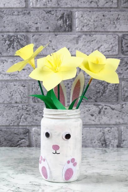 DIY Easter vase bunny from glass jar, felt, googly eyes on a green background stock photo