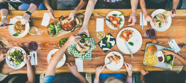 eating and leisure concept - group of people having dinner at table with food - pizza table imagens e fotografias de stock