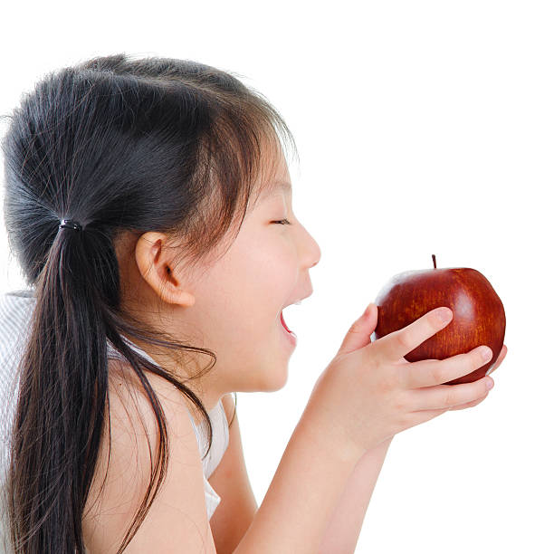 Eating Apple Little Asian girl eating apple on white background child korea little girls korean ethnicity stock pictures, royalty-free photos & images