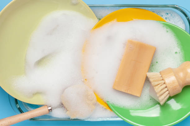 Eco concept. Washing dishes with soap. Soap foam plates and bamboo washing brushes. Zero waste. Top view stock photo