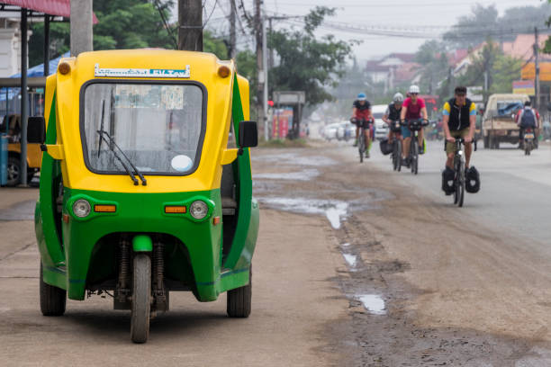 Eco-friendly electronic tuk tuk in Luang Prabang, Laos. Green and yellow vehicle. Car rickshaw in Asia. stock photo