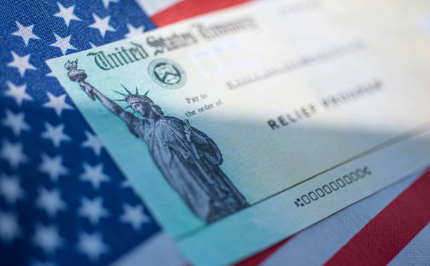 COVID-19 economic Stimulus check on blurred USA flag background. Relief program concept. Washington, DC, USA - March, 16, 2020: stimulus check stock pictures, royalty-free photos & images