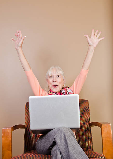 Ecstatic Senior Woman Using Laptop Computer stock photo