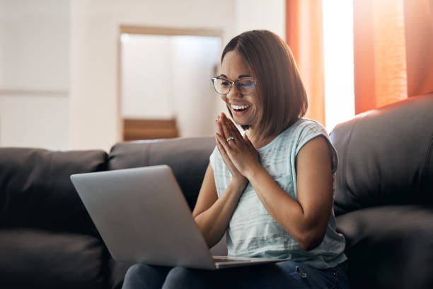 Ecstatic that I finally finished all my work Cropped shot of an attractive young woman using a laptop at home ecstatic stock pictures, royalty-free photos & images