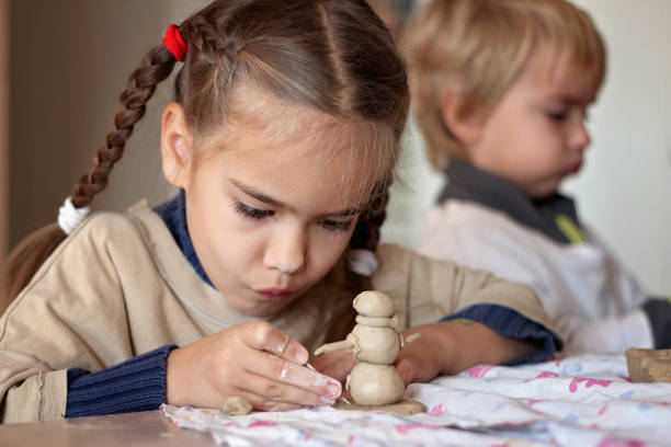 Education and art, kid playing with modeling clay in pottery workshop, craft and clay art stock photo
