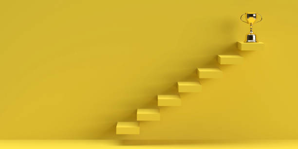 Efficient climbing ladder blocks in yellow with golden trophy on top and copy space stock photo