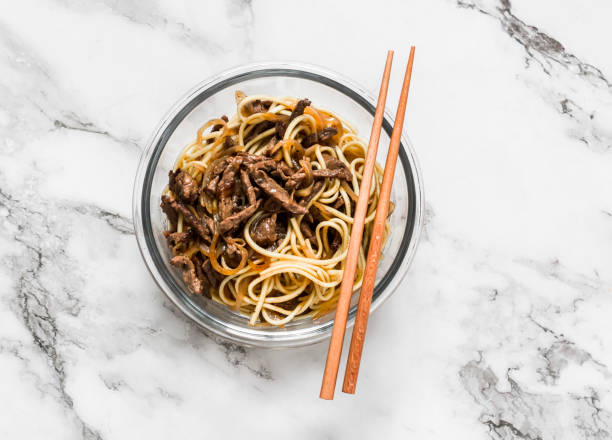 Egg noodles with spicy beef stir fry - asian style lunch on a light background, top view stock photo