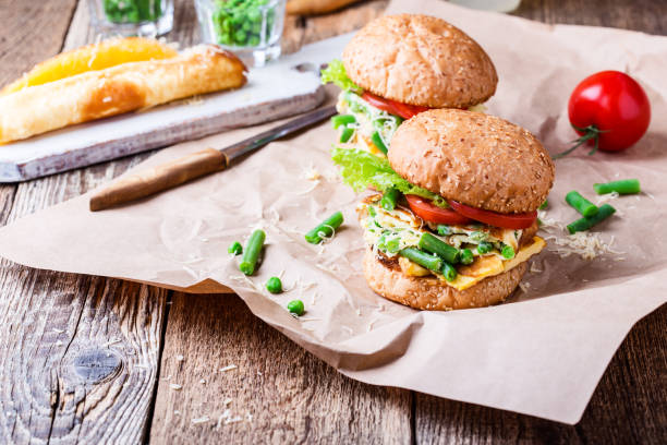 Egg omelet burger with  green beans and peas filling Egg omelet burger with  green beans and peas filling  on rustic wooden table, delicious  picnic snack in rural style burger wrapped in paper stock pictures, royalty-free photos & images