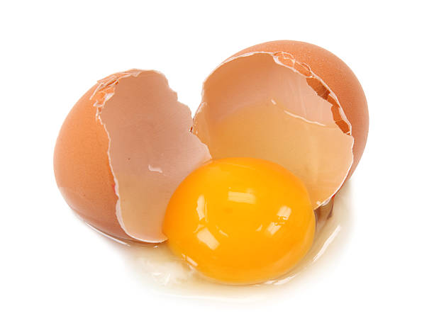 Egg shell broken in middle with yolk and white spilling out stock photo