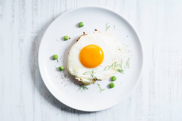 egg toast fried egg with toasted bread decorated with green pea on white plate. breakfast dish. fried egg photos stock pictures, royalty-free photos & images