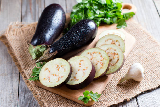Eggplant slices on cutting board on wooden background Eggplant slices on cutting board on wooden background eggplant stock pictures, royalty-free photos & images