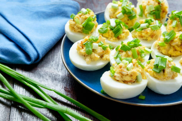 Eggs stuffed with green onion on a blue plate on a wooden background stock photo