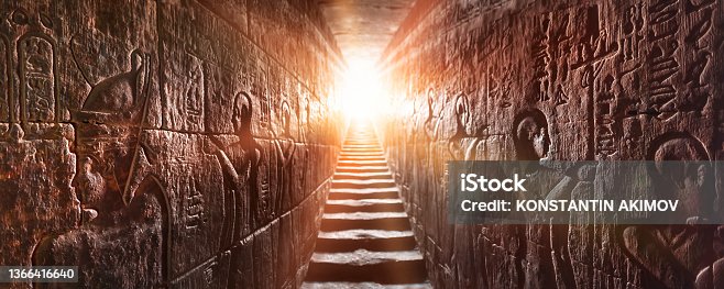 istock Egypt Edfu temple, Aswan. Passage flanked by two glowing walls full of Egyptian hieroglyphs, illuminated by a warm orange backlight from a door 1366416640