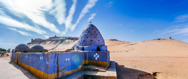 Egypt, Upper Egypt, Aswan, Blue painted Beehive Mausoleum with Tomb of the Nobles on hilltop behind. Egypt, Upper Egypt, Aswan, Blue painted Beehive Mausoleum with Tomb of the Nobles on hilltop behind. aswan egypt stock pictures, royalty-free photos & images