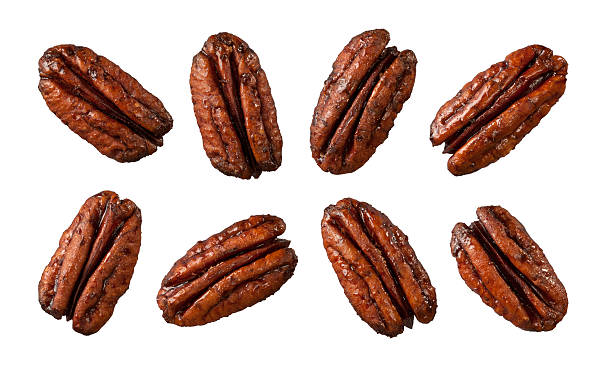 eight caramelized pecans isolated on white - pecannoot stockfoto's en -beelden