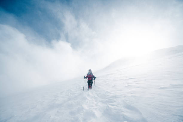 пожилой альпинист зимой поднимается на вершину высокогорной горы - blizzard стоковые фото и изображения