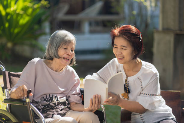 Elderly and daughter reading a book together for improves memory and helps prevent dementia. stock photo