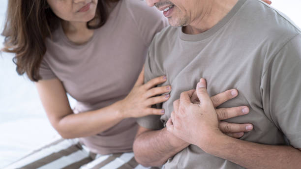 Elderly Asian man with chest pain from a heart attack, His wife was worried when she saw her husband sick, congenital disease, Heart disease, High blood pressure. stock photo