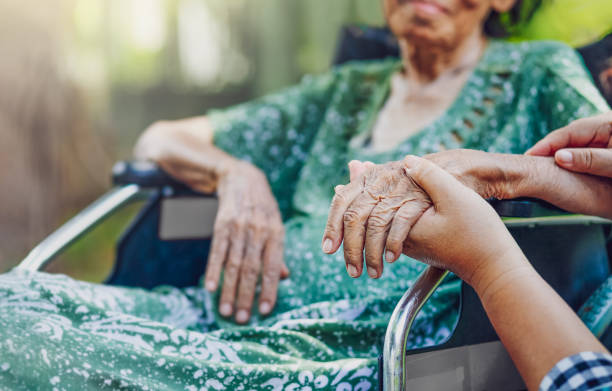 oudere aziatische vrouw op rolstoel thuis met dochter zorg - bejaardenhuis stockfoto's en -beelden