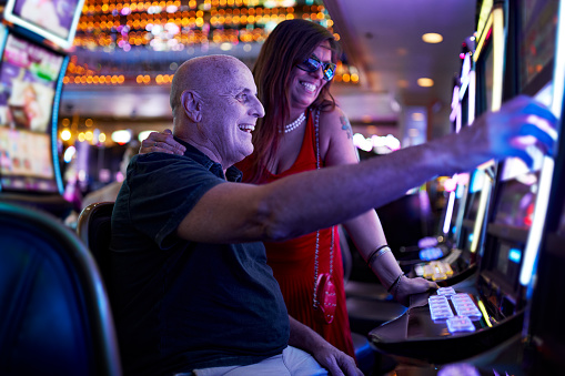 Elderly Couple Gambling On Slot Machine In Casino Stock Photo - Download  Image Now - iStock