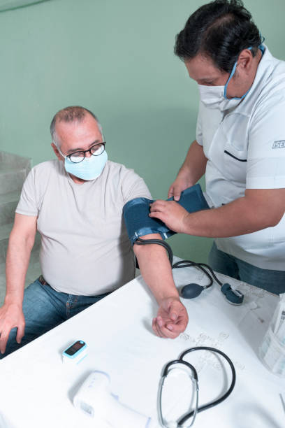 elderly Latino man in a test with a Hispanic doctor to measure his blood pressure as a preventive measure for diseases stock photo