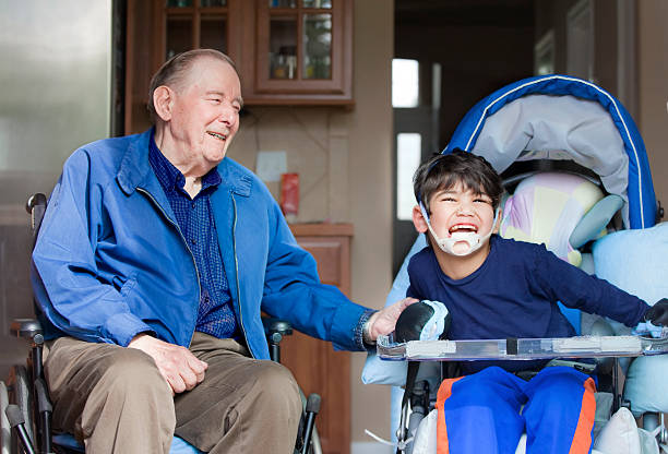 Elderly man and disabled boy both in wheelchairs together stock photo