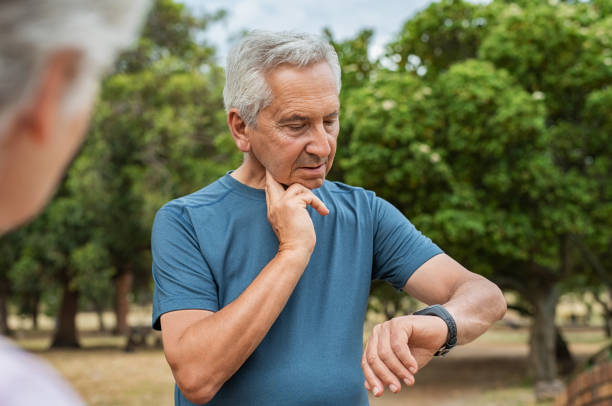 Elderly man checking pulse after running Senior tired man checking pulse after workout. Old man measuring heart rate pulse on his neck and looking sport watch. Aged man times the pulsations at park. taking pulse stock pictures, royalty-free photos & images