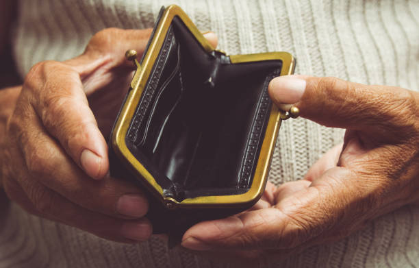 Elderly man holds in his hands an empty wallet. Vintage empty purse in wrinkled hands . Poverty in retirement concept. Special toning stock photo