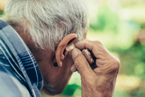 пожилой человек вставки его слуховой аппарат - hearing aids стоковые фото и изображения