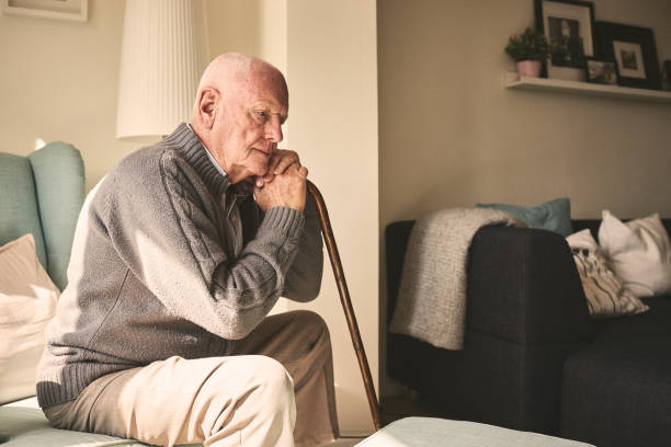 Elderly man sitting alone at home Thoughtful elderly man sitting alone at home with his walking cane solitude stock pictures, royalty-free photos & images