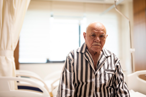 Elderly men is sitting on hospital bed before surgery