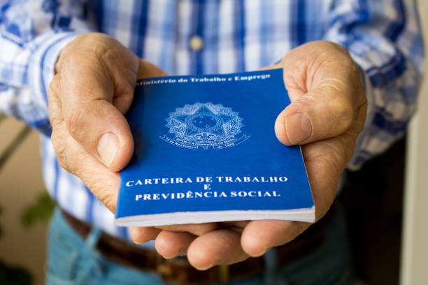 Elderly old male hands worker holding portfolio work permit of Ministry of Labor and Social Security of Brazil(Translation: "Work Permit, Ministry of Labor and Social Security of Brazil CTPS"). stock photo