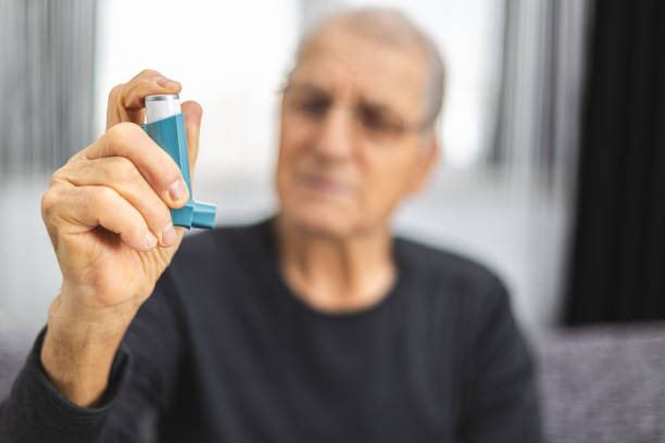 ältere menschen mit einem asthmaspray. senior mann bereit für die verwendung eines asthma-inhalators - asthmainhalator stock-fotos und bilder