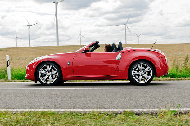 Elderly woman drives Nissan Convertible "Trebus, Germany - August 10, 2012: Elderly woman driving a Nissan 370Z Roadster. The Nissan 370Z Roadster is a convertible model from Nissan. Nissan Motor Co. Ltd. is a multinational car manufacturer headquartered in Japan and global car company." vertical axis wind turbine stock pictures, royalty-free photos & images