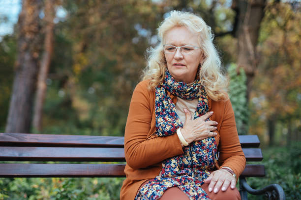 äldre kvinna med bröstsmärtor eller hjärtattack i parken - medelålders kvinna bröstsmärtor bildbanksfoton och bilder