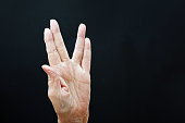 Senior woman makes a hand sign.