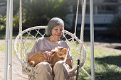 裏庭の車椅子で生姜猫を飼っている高齢の女性。