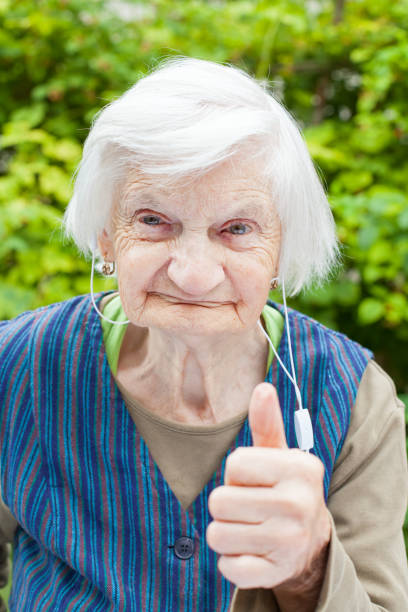 starsza kobieta słuchając muzyki ze słuchawkami - hearing aids zdjęcia i obrazy z banku zdjęć