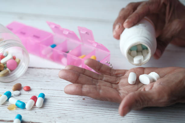 anziana donna versando pillole dalla bottiglia a portata di mano, vista dall'alto - farmaco foto e immagini stock