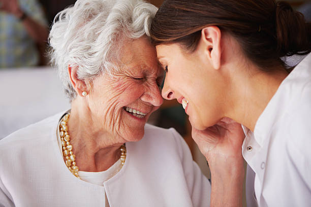 Elderly woman touching face of young female nurse An elderly woman affectionately thanking her nurse love emotion stock pictures, royalty-free photos & images