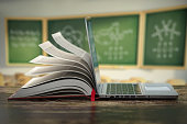 istock E-learning online education or internet  encyclopedia concept. Open laptop and book compilation in a classroom. 1263424631